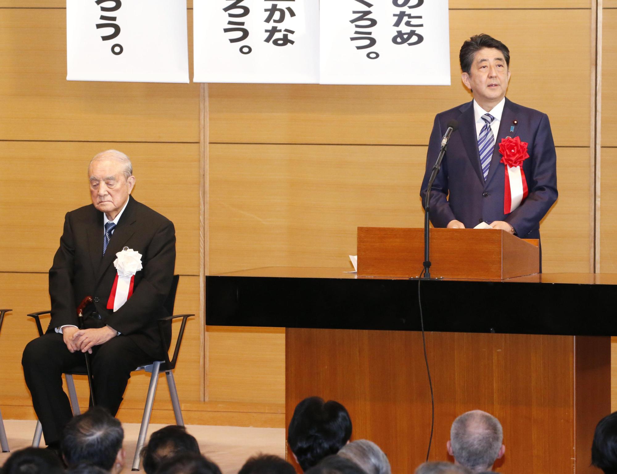 Prime Minister Shinzo Abe speaks at a gathering in Tokyo Monday of a cross-party league of lawmakers who favor amending the Constitution, alongside former Prime Minister Yasuhiro Nakasone. | KYODO