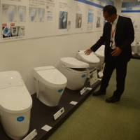 Ikuya Idota of Lixil Group Corp. shows generations of toilets with built-in spray wash displayed at the firm’s factory in Tokoname, Aichi Prefecture. Pioneering Aichi firm that brought electronic toilets to the next level