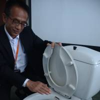 Ikuya Idota of Lixil Group Corp. shows the first Japan-made toilet with a built-in spray wash developed by Ina Seito Co., predecessor of Lixil, in 1967. | CHUNICHI SHIMBUN