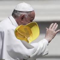 Pope Francis is partially covered by a hat tossed by a faithful as waves to the crowds at the end of a general audience he held in St. Peter\'s Square at the Vatican Wednesday. | AP