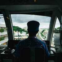 Cool biz: A monorail conductor in Naha sports an Okinawan Kariyushi shirt. | ANDREW CURRY