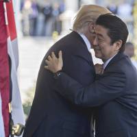 U.S. President Donald Trump greets Prime Minister Shinzo Abe as he arrives in the West Wing of the White House at the start of their summit on Feb. 10. | BLOOMBERG