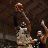 Ryukyu’s Reyshawn Terry puts up a shot as Osaka’s Josh Harrellson defends during Sunday’s game in Okinawa City. The Golden Kings won 80-72.  | B. LEAGUE