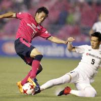 Cerezo Osaka\'s Ryuji Sawakami (left) tries to control the ball while being challenged by Vissel Kobe\'s Takuya Iwanami during their Levain Cup match on Wednesday. Cerezo won 1-0. | KYODO