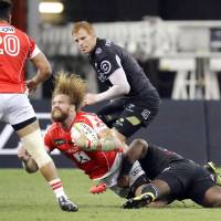 The Sharks\' Tendai Mtawarira tackles the Sunwolves\' Willie Britz during Saturday\'s Super Rugby match in Singapore. | KYODO