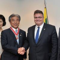 Lithuanian Foreign Minister Linas Linkevicius (center right) shakes hands with Hirofumi Nakasone, chairman of the Japan-Lithuania Parliamentary Friendship League, after receiving the Lithuanian Diplomacy Star during a reception at the embassy on May 10. Others pictured are (from left) Nakasone\'s wife, Mariko, Lithuanian Ambassador Egidijus Meilunas and his wife, Galina. | YOSHIAKI MIURA