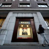 A pedestrian walks past the Nomura Securities headquarters in Tokyo. The firm bought about &#36;100 million worth of Venezuelan government bonds last week as part of the same transaction that landed Goldman Sachs Group in the middle of a political storm, the Wall Street Journal reported. | BLOOMBERG
