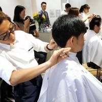 A barber cuts hair at QB House\'s first outlet in New York on Thursday. | KYODO