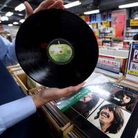 A shop manager shows off a period Japanese pressing of The Beatles\' final studio album \'Let It Be\' at the RECOfan music shop in Tokyo\'s Shibuya district on Thursday. Sony said it will start making vinyl records again on the back of surging demand for a technology that the Japanese firm abandoned three decades ago. | AFP-JIJI