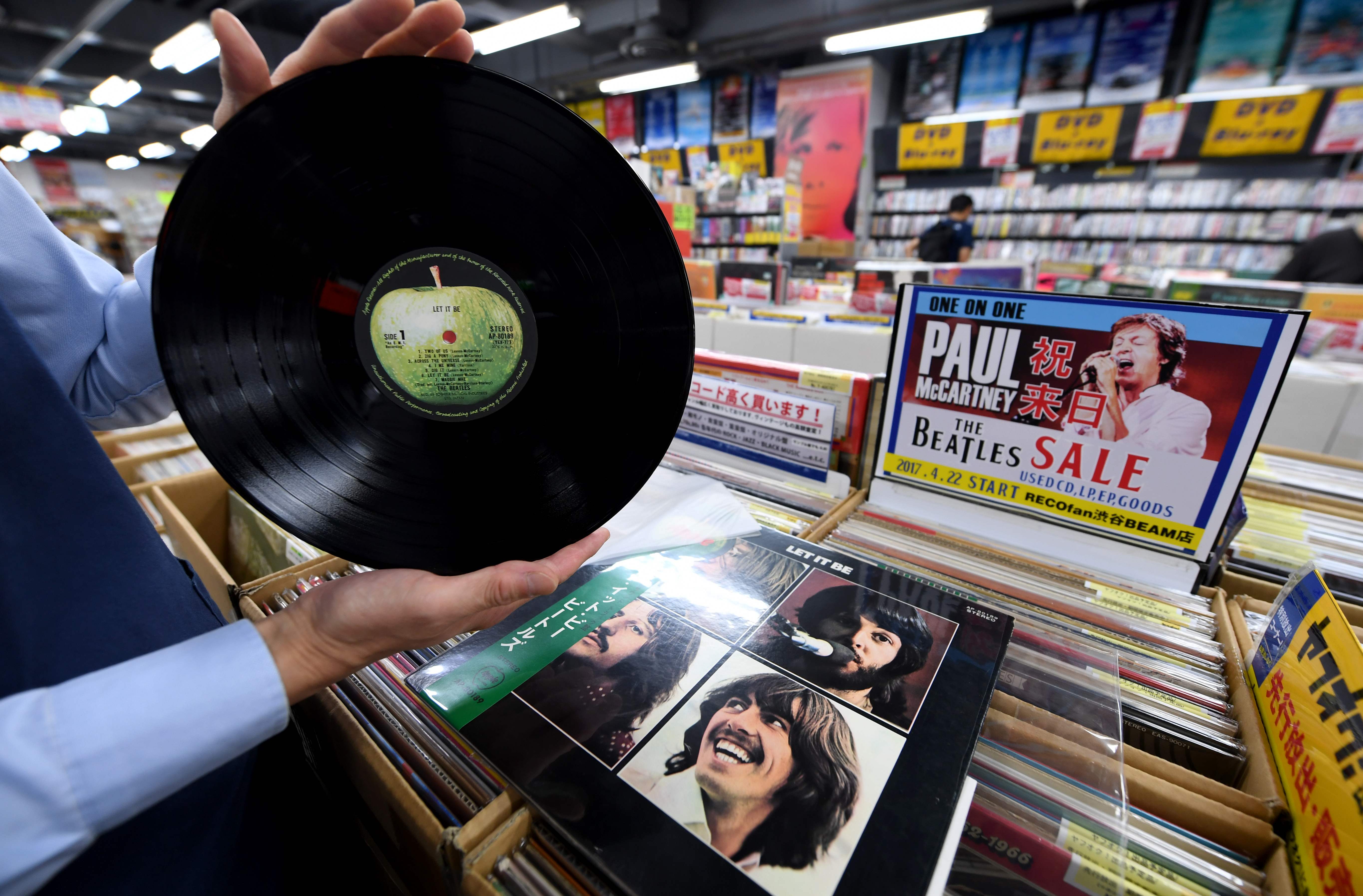 A shop manager shows off a period Japanese pressing of The Beatles' final studio album 'Let It Be' at the RECOfan music shop in Tokyo's Shibuya district on Thursday. Sony said it will start making vinyl records again on the back of surging demand for a technology that the Japanese firm abandoned three decades ago. | AFP-JIJI