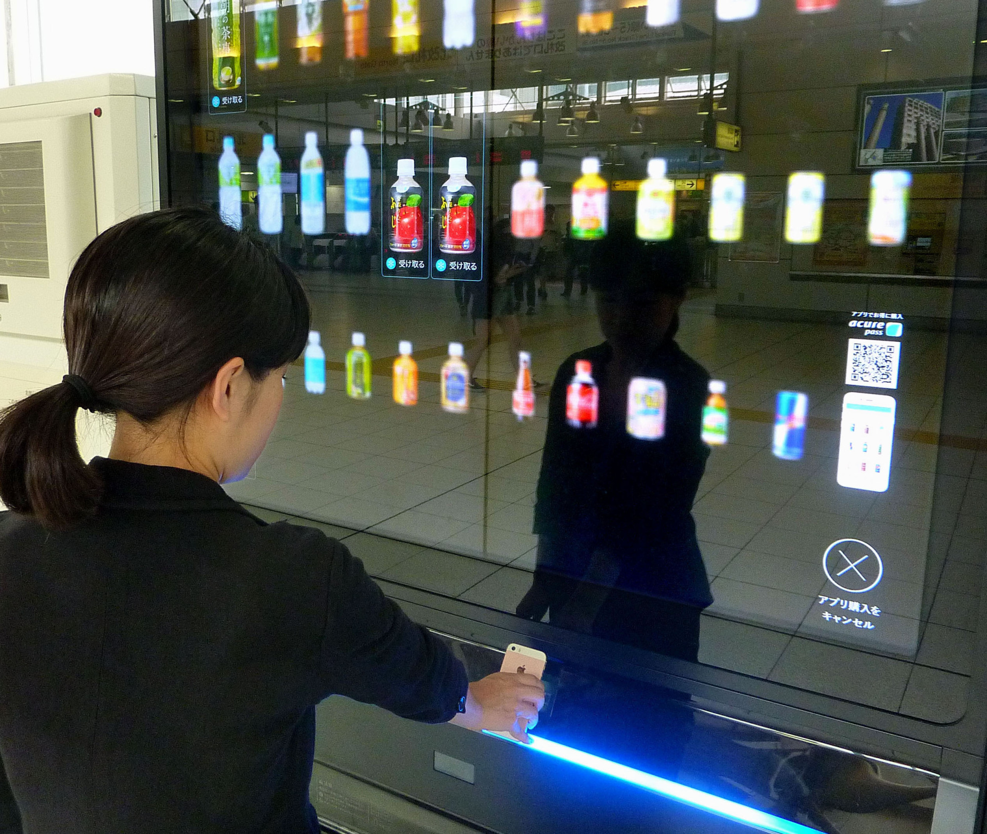 A model demonstrates how to buy drinks with a smartphone from a vending machine owned by JR East Water Business Co. | KYODO