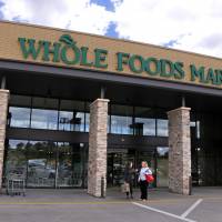 People stand outside a Whole Foods Market in Upper Saint Clair, Pennsylvania, in May. Amazon’s planned $13.7 billion acquisition of Whole Foods signals a massive bet that people will opt more for the convenience of online orders and delivery or in-store pickup, putting even more pressure on the already highly competitive industry. For purist Whole Foodies, Amazon's takeover triggers downmarket angst
