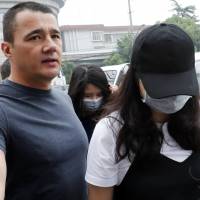 Crown Resorts employee Jiang Ling (rear center) and another employee wearing a face mask, arrive at the Baoshan District People\'s Court to attend their trial in Shanghai on Monday. | AP