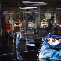 Women look at specially made Italian luxury fashion brand handbags on display at an exhibition in Beijing on Friday. | AP