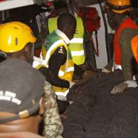 Rescue workers remove the body of a woman from a collapse building in Nairobi Tuesday. Rescuers pulled a child and the child’s mother from the rubble of an eight-story building Tuesday that had collapsed in a low-income part of Kenya’s capital, while three people were thought to remain trapped in the debris. Most believed evacuated before seven-floor building collapsed in Nairobi; trio rescued