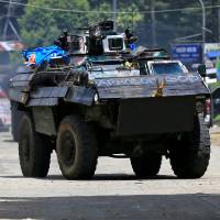 An armored personnel carrier drives along a road in Amai Pakpak on Wednesday as government troops continued their assault against insurgents from the Maute group, who have taken over large parts of the city of Marawi. | REUTERS