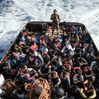 A Libyan coast guardsman stands on a boat during the rescue of 147 illegal immigrants attempting to reach Europe off the coastal town of Zawiyah, 45 km west of Tripoli, on Monday. More than 8,000 migrants have been rescued off Libya during the past 48 hours in difficult weather conditions, Italy\'s coast guard said on Tuesday. | AFP-JIJI