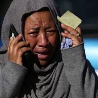 A woman tries to locate a relative feared missing in the Grenfell Tower fire in London on Wednesday. Stay or go? Deadly London fire puts scrutiny on high-rise rule