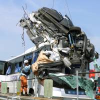 A car that crashed into a bus on the Tomei Expressway in Aichi Prefecture on Saturday is hoisted by crane.  The driver died at the scene. | TOSHIN KANKO BUS CO.