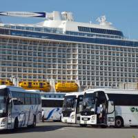 Tour buses wait in front of a cruise ship at Hakata Port in Fukuoka in August 2016. A law was enacted Friday to upgrade key ports to attract more tourism via cruise ships. | KYODO