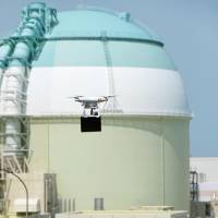 A drone carrying a black box flies near reactor 3 at the Ikata nuclear power plant in Ehime Prefecture on Monday, in the nation\'s first counterterrorism drill to simulate a drone attack on a nuclear facility. | KYODO