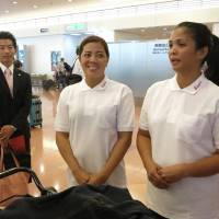 Jocelyn Paloma Oledan (center) and Marianne Paragua Culaniban, who arrived from the Philippines on Wednesday to work as housekeepers in Tokyo, speak to reporters at Haneda airport. | KAZUAKI NAGATA