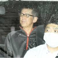 Masaaki Osaka sits in the back seat of a police car after he was served with a fresh arrest warrant on Wednesday in Osaka. | KYODO