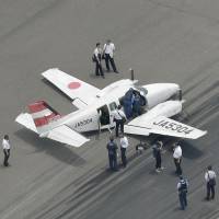 A small twin-propeller plane that made a belly landing sits on the tarmac at Nagasaki airport on Thursday. | KYODO