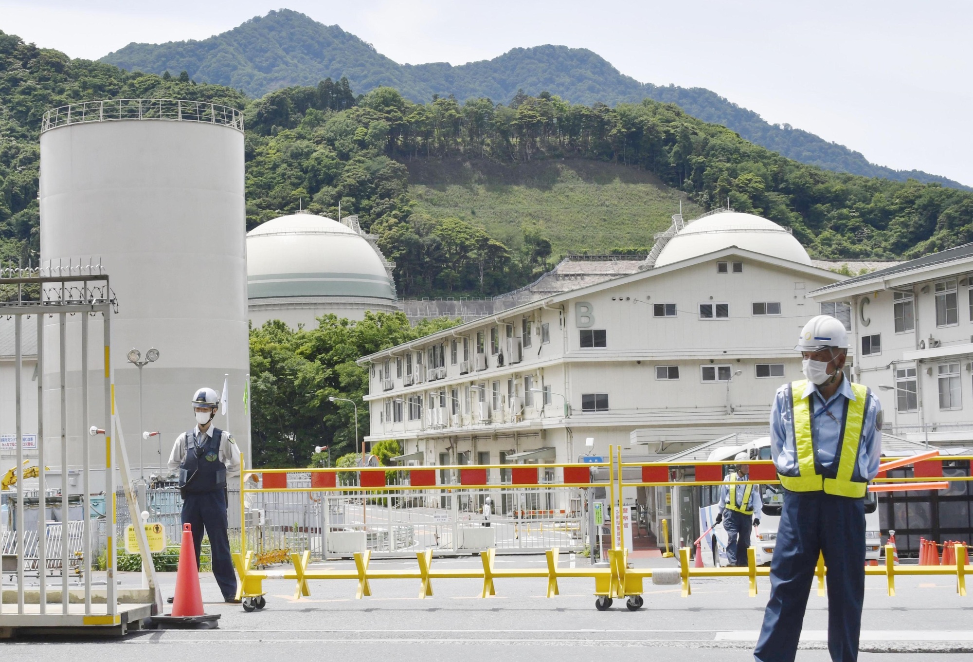 Security guards stand near a gate at the Takahama nuclear power plant in Takahama, Fukui Prefecture, on Tuesday, prior to the restart of a reactor at the facility. | KYODO