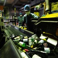 Crates of bottles are emptied onto a conveyor belt at the Minato Resource Recycle Center in Tokyo. | TIM HORNYAK