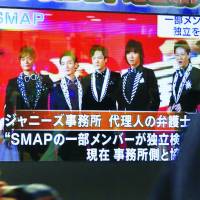 Farewell Johnny: Passersby watch the news of SMAP\'s breakup on a TV screen in 2016 in Tokyo. | KYODO