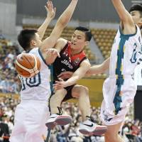 Yuki Togashi passes the ball around a Macau defender during Japan\'s 119-47 win at the East Asia Basketball Championship in Nagano on Sunday. | KYODO