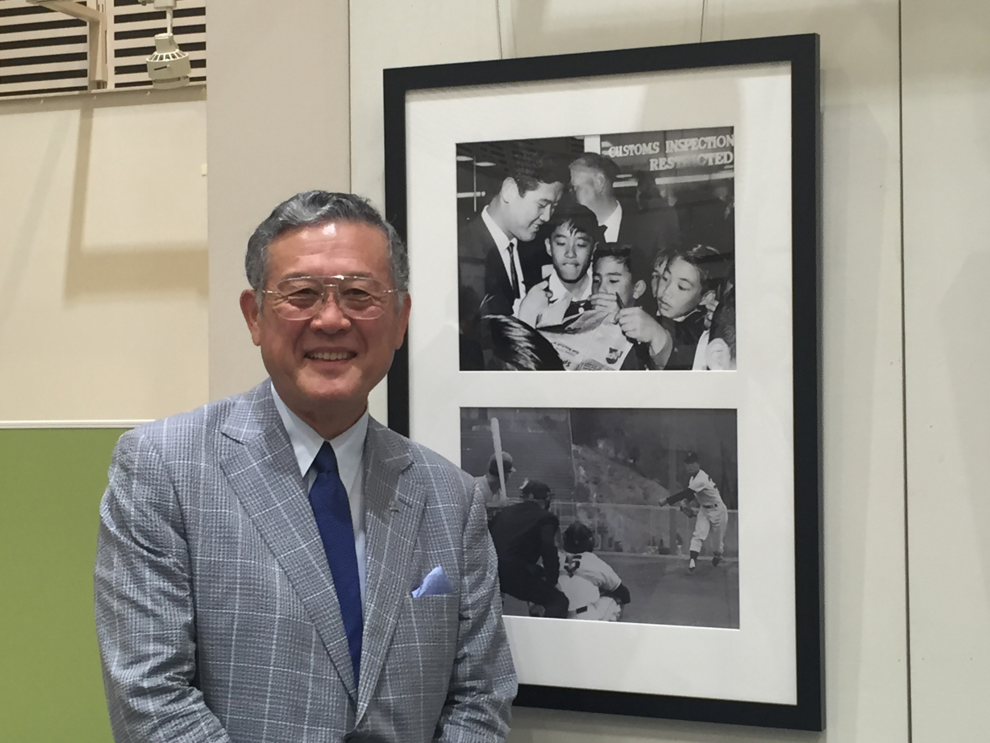 Masanori Murakami poses in front of photos of himself at the Pacific Pitch: U.S.-Japan Baseball Diplomacy exhibition Thursday at Tokyo Metropolitan Central Library on Thursday. | JASON COSKREY