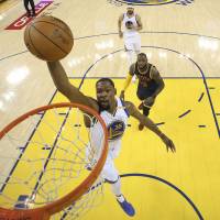 The Warriors’ Kevin Durant dunks in front of the Cavaliers’ LeBron James during the first half of Game 1 of the NBA Finals on Thursday in Oakland, California. Durant, Curry ignite Warriors in Game 1 rout of Cavaliers