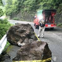 A photographer snaps shots of two boulders that fell onto a road in the village of Otaki, Nagano Prefecture, on Sunday after a quake that registered an upper 5 on the Japanese seismic intensity scale to 7 rocked the area early that morning. | KYODO