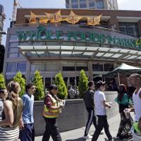 Pedestrians walk past a Whole Foods Market just down the street from the headquarters of Amazon in Seattle Tuesday. Amazon, already a powerhouse in books, shoes, streaming video, electronics and just about everything else, will bind its customers even more closely once it completes its $13.7 billion bid for the organic grocer Whole Foods. Although antitrust lawyers believe the deal will get approved, many customers and experts alike worry about two big companies combining into a bigger one. Amazon may defy definition of monopoly but it's got solid 'intimidating' lock on consumers