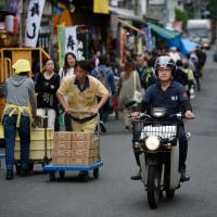 A man rides a Honda Motor Co. Super Cub at the Tsukiji market in Tokyo on June 13. Japan's 'Monkey Bike' nears extinction as country cuts tailpipe emissions