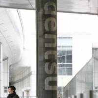 A woman walks with a girl in front of a sign for Dentsu Inc. in Tokyo. Dentsu barred for month from bidding on industry ministry contracts due to labor violations
