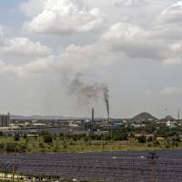 Industrial buildings stand beyond DMICDC Neemrana Solar Power Co.’s solar panels at the Rajasthan State Industrial Development and Investment Corp.’s industrial complex in Neemrana, India, in June. Japanese companies find an island of calm in India's chaotic business terrain