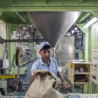A worker packs plastic pellets into sacks at Dainichi Color India\'s factory in the Rajasthan State Industrial Development and Investment Corp,\'s industrial complex in Neemrana, India, in June. | BLOOMBERG