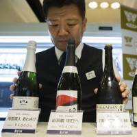 A member of the Japan Awasake Association displays bottles of sparkling sake, including one brewed by Nanbu-Bijin (left), at the association’s booth during a Sake Marche event at the Isetan Shinjuku department store in Tokyo on June 28. Sake makers tout locally sourced rice to entice terroir-obsessed wine enthusiasts