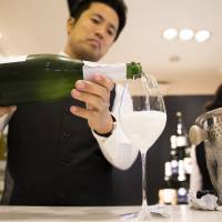 A member of the Japan Awasake Association pours a glass of Nanbu Bijin Asa Wake Sparkling sake, brewed by Nanbu Bijin Co., during a Sake Marche event at the Isetan Shinjuku department store in Tokyo on June 28. | BLOOMBERG