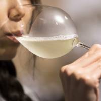 A customer drinks a glass of sparkling sake at the Japan Awasake Association booth during a Sake Marche event at the Isetan Shinjuku department store in Tokyo on June 28. | BLOOMBERG