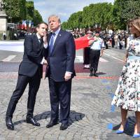 French President Emmanuel Macron shakes hands with U.S. President Donald Trump next to U.S. first lady Melania Trump during the traditional Bastille Day military parade on the Champs-Elysees avenue in Paris on Friday. | REUTERS