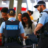 Australian Federal Police officers talk with passengers near the check-in counters at Sydney Airport on Sunday. Terrorists who wanted to down Australian plane may have planned to use bomb or gas: reports