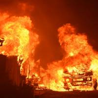 A car and house are engulfed in flames as the “Wall Fire” burns through a residential area in Oroville, California, Saturday. The first major wildfires after the end of California’s five-year drought raged across the state as it was gripped by a record-breaking heatwave. Northern California besieged again, this time by wildfires