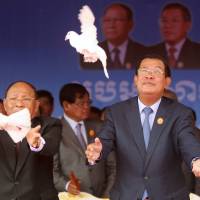 Cambodian Prime Minister Hun Sen (right), who is also president of the ruling Cambodian People’s Party, releases doves with and National Assembly head Heng Samrin during a ceremony to mark the 66th anniversary of the establishment of the party in Phnom Penh on June 28. Cambodia OKs bill tightening screws on opposition