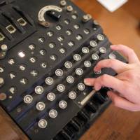 An employee of an auction house presses a key on an working original Enigma cipher machine on display at an auction house in Bucharest on Tuesday. | REUTERS