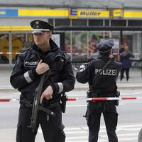 Police officers secure the area after a knife attack at a supermarket in Hamburg, Germany, on Friday. Known knife-wielding Islamist kills one, injures six in Germany