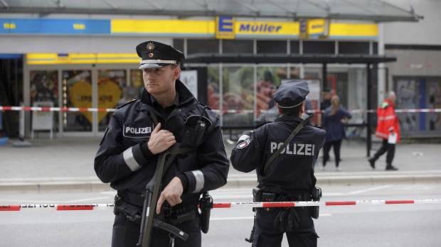 Police officers secure the area after a knife attack at a supermarket in Hamburg, Germany, on Friday. Known knife-wielding Islamist kills one, injures six in Germany